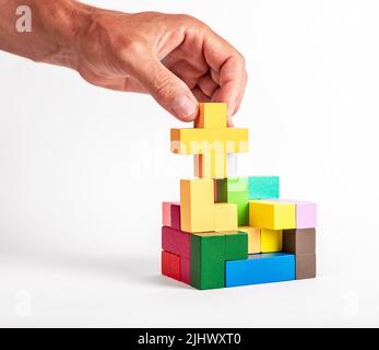 Uomo che mette insieme gli elementi del puzzle nella costruzione. Assemblaggio, concetto di ingegneria. Bambini o giocattolo di famiglia per l'intelligenza, il pensiero logico, lo sviluppo di creatività, il miglioramento di concentrazione. Foto Foto Stock