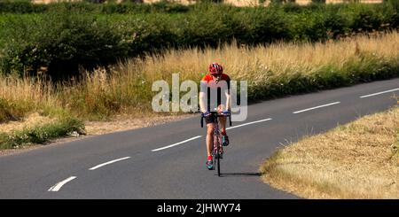 Lycra clad ciclista su una strada di campagna Foto Stock