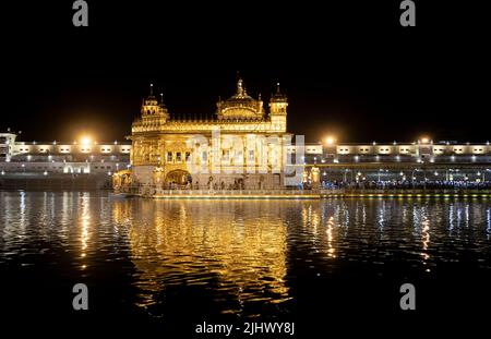 Amritsar, Punjab, India - Maggio 20th 2022: Pellegrini riuniti al Tempio d'Oro di Amritsar illuminato di notte Foto Stock