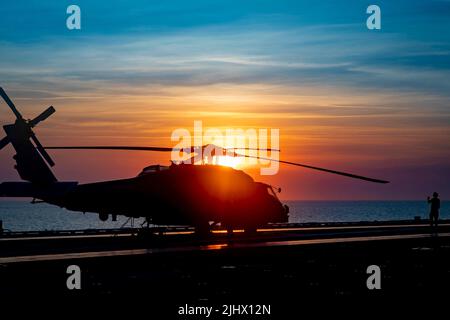 23 giugno 2022 - Oceano Atlantico - Un marinaio assegnato alla Carrier Air Wing (CVW) 7 segnala un MH-60R Sea Hawk elicottero attaccato al Maritime Strike Squadron (HSM) 46, 23 giugno 2022. The George H.W. Bush Carrier Strike Group (CSG) sta completando un esercizio di certificazione per aumentare l'interoperabilità e la capacità di combattimento degli Stati Uniti e degli alleati prima di un'implementazione futura. The George H.W. Bush CSG è un sistema integrato di armi da combattimento che offre una capacità di combattimento superiore per scoraggiare e, se necessario, sconfiggere gli avversari americani a sostegno della sicurezza nazionale. L'ala pneumatica portante (CVW) 7 è la Foto Stock