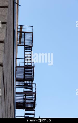 Silhouette di una fuga di fuoco su un alto edificio contro un cielo blu Foto Stock