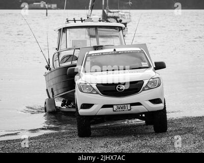 Mazda BT-50 Generation II (2011-2015) bianco, autocarro che tira fuori dall'acqua la traina di un rimorchio di Fyran. Auckland, Nuova Zelanda - 8 giugno 2022 Foto Stock