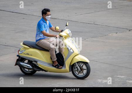 SAMUT PRAKAN, THAILANDIA, MAR 29 2022, un uomo con maschera di faccia corre una moto Foto Stock