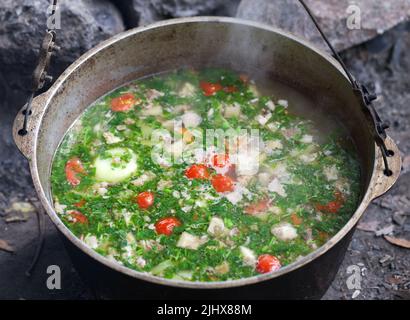 Cucinata fresca zuppa calda nel calderone di fuliggine al camping. Cucina outdoor. Foto Stock