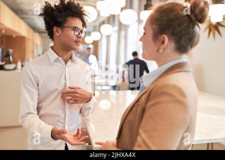 Fondatore africano della startup e giovane collega che ha un piccolo colloquio nell'agenzia creativa Foto Stock