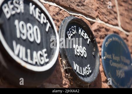 Villaggio di Eccleston, Inghilterra. Vista ravvicinata pittoresca delle targhe Best Ked Village Year, montate su un muro a Eccleston’s Hill Road. Foto Stock