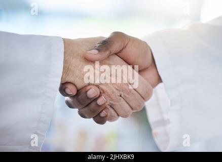 Primo piano di mani di due medici che si salutano con una stretta di mano. Medico afroamericano scuotendo le mani con il medico caucasico in ospedale Foto Stock