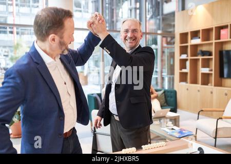 Gli uomini d'affari si divertono a giocare a calcio balilla in ufficio e a darsi un alto cinque Foto Stock