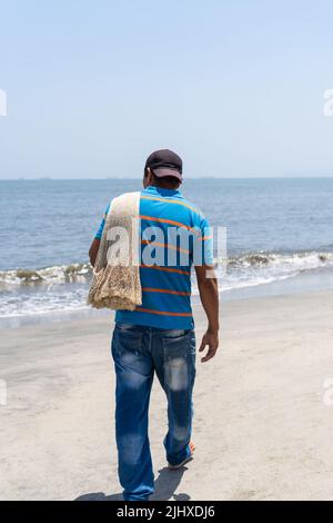 Pescatore a piedi con rete da pesca che si prepara ad andare al mare Foto Stock