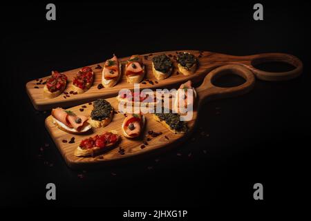 Una Bruschetta con diversi condimenti servita su una scrivania decorativa in legno Foto Stock