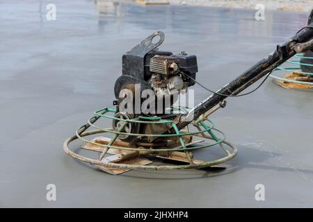 I lavoratori utilizzano macchine per la lucidatura del cemento dopo aver versato il calcestruzzo sul pavimento della fondazione. Foto Stock