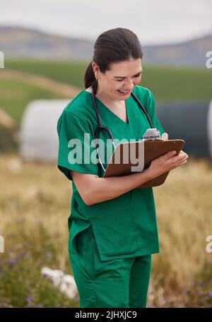 Creazione di procedure di gestione per salute branco migliore. Un giovane veterinario scrivere note su una clipboard mentre si lavora su un allevamento di pollame. Foto Stock