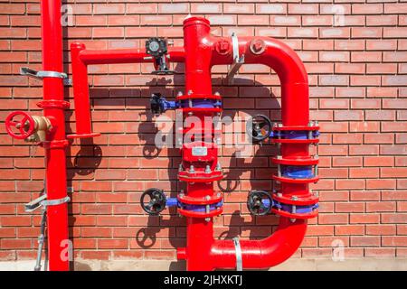 Nuovo edificio del magazzino di fabbrica costruito con tubi ad alta pressione acqua valvole di sicurezza antincendio unità montata all'esterno sulla parete degli edifici. Foto Stock