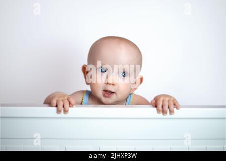 cute cute bambino peeking fuori su sfondo bianco. Foto Stock