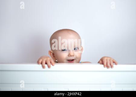 cute cute bambino peeking fuori su sfondo bianco. Foto Stock