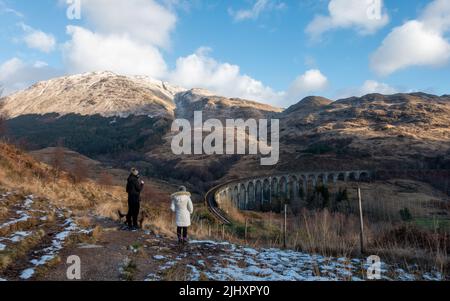 Paesaggio scozzese e passeggiate invernali: Persone che godono la vista della neve sulle piste del viadotto Glenfinnan, Scozia Foto Stock