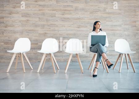 Ho tanto da fare. Scatto a tutta lunghezza di una giovane donna d'affari attraente seduta da sola in ufficio e guardando contemplativo mentre Foto Stock