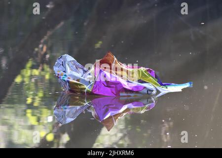 L'inquinamento ambientale, un palloncino di elio non biodegradabile, crollò e galleggiò lungo un fiume. Foto Stock