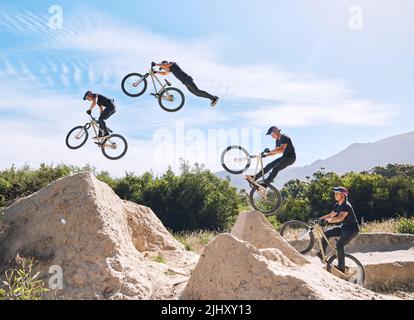 Giovane uomo che mostra le sue abilità ciclistiche mentre fuori in bicicletta su una bicicletta fuori. Adrenalina junkie praticare un salto di sporcizia all'aperto. Maschio che indossa un casco Foto Stock