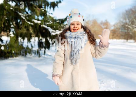 piccola ragazza felice che ondina la mano all'aperto in inverno Foto Stock