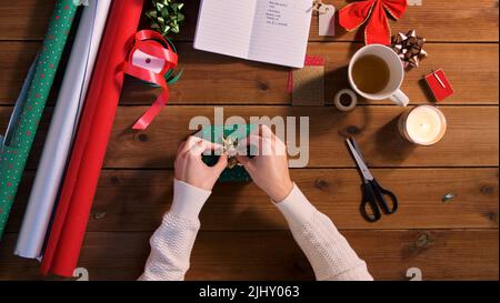 mani che imballano il regalo di natale e che attaccano l'arco Foto Stock