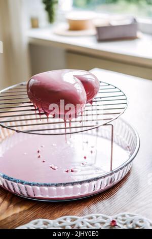 Torta di mousse. Torta di smalto a specchio. Processo di fabbricazione della torta di mousse a forma di cuore con smalto a specchio rosa Foto Stock