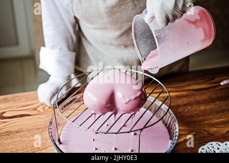 Torta di mousse. Torta di smalto a specchio. Processo di fabbricazione della torta di mousse a forma di cuore con smalto a specchio rosa Foto Stock