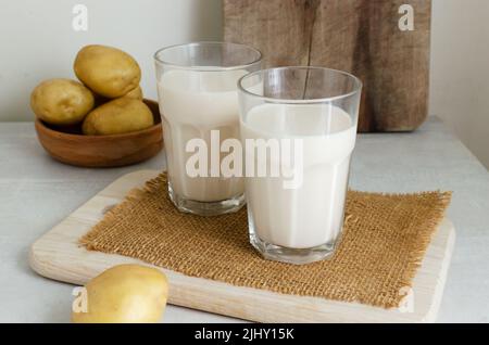 Due bicchieri di vetro con latte di patate. Stile rustico. Una nuova tendenza nel mangiare sano. Concetto di cibo alternativo. Latte vegetale per vegani. Orizzontale orien Foto Stock