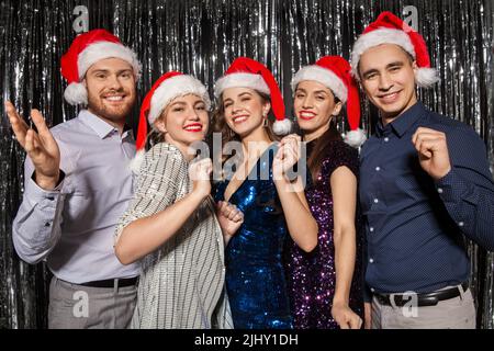 Happy amici in cappelli di Babbo Natale alla festa di natale Foto Stock