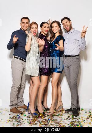 amici felici a festa con confetti sul pavimento Foto Stock