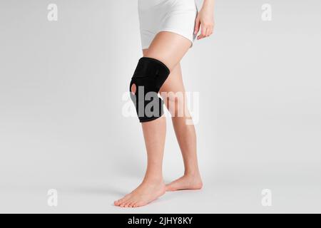 Supporto ginocchia su gamba isolata su sfondo bianco. Ortosi ortopedica elastica. Bretelle anatomiche per fissazione del ginocchio, lesioni e dolore. Protezione Foto Stock
