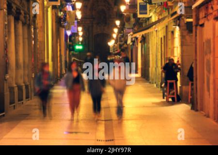 Immagine sfocata di San Sebastian tipica vista su una piccola strada con tapas bar animati e ristoranti di notte Foto Stock