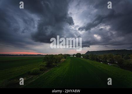 I campi agricoli lungo il Danubio contro le scure nuvole tempestose in Baviera, Germania Foto Stock