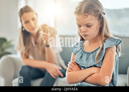 Primo piano di una bambina adorabile in piedi con le braccia incrociate e guardare sconvolto, mentre essere scolded e rimprovero da lei arrabbiato e deluso Foto Stock