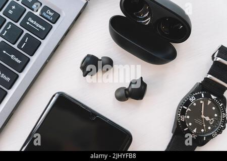 Notebook, smartphone, cuffie wireless e orologio su sfondo bianco. Gadget moderni. Vista dall'alto Foto Stock