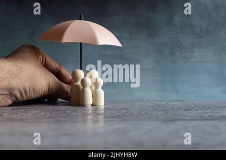 Ombrello e bambole in legno con spazio copia. Concetto di protezione della famiglia e copertura assicurativa. Foto Stock