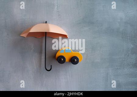 Ombrello e auto giocattolo con spazio per fotocopie. Protezione dell'auto e concetto di assicurazione. Foto Stock
