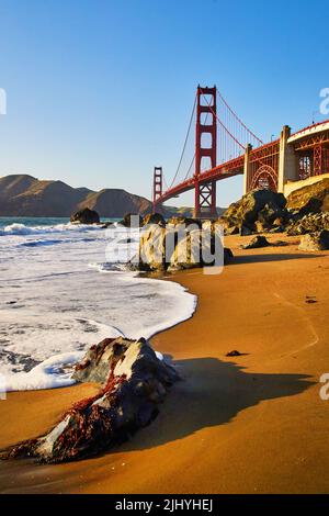Ondeggia sulle splendide spiagge accanto al Golden Gate Bridge con luce dorata dal tramonto Foto Stock