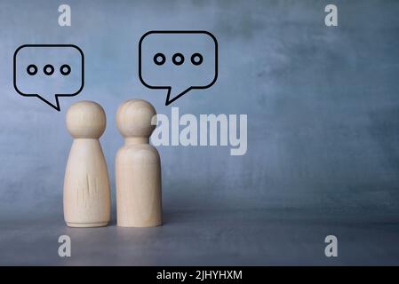 Bambole in legno e bolla vocale con spazio per la copia. Concetto di comunicazione e di interazione sociale. Foto Stock