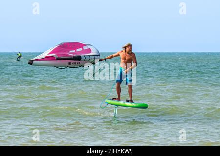 Alare / alare surf sul Mare del Nord mostra wingboarder / alare boarder in piedi su foilboard / aliscafo e tenendo un'ala gonfiabile Foto Stock