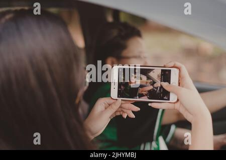 adolescente fotografando un'altra persona con un telefono bianco Foto Stock