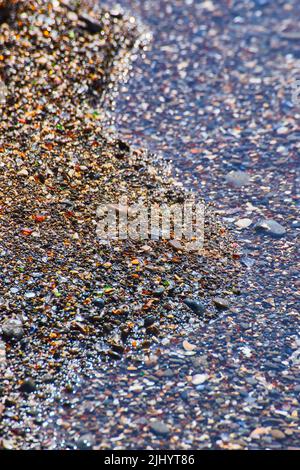 Acqua sulla costa di spiaggia di vetro coperta di pezzi di vetro Foto Stock