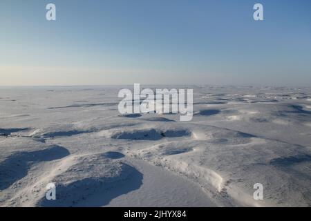 Vista aerea della tundra artica ghiacciata coperta di neve, al di fuori di Tuktoyaktuk, territori nordoccidentali, Artico occidentale, Canada. Foto Stock