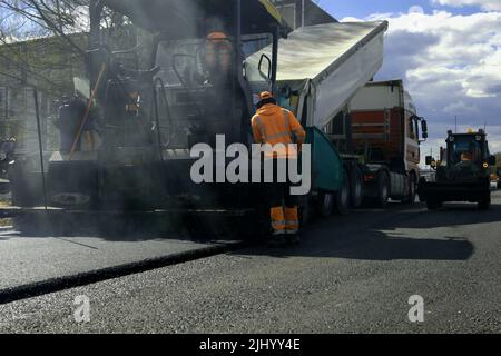 operatore asfaltatrice. macchina asfaltatrice in cantiere. processo di rinnovo, lavori di costruzione. Vista ad angolo alto Foto Stock