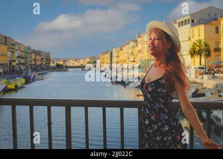 Giovane donna asana in abito estivo in piedi sul ponte di Sete, una delle destinazioni più importanti nella regione dell'Occitanie, nel sud della Francia Foto Stock