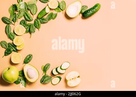 Frutta e verdura fresche verdi, spinaci, mela, lime, avocado, cetriolo sfondo marrone chiaro Foto Stock