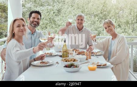 Un pasto in famiglia dovrebbe essere servito con risate e amore. Una famiglia tostatura con bicchieri di vino a casa. Foto Stock