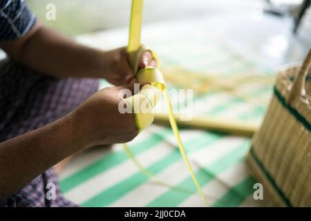 Tessendo le foglie di cocco che fanno il ketupat, una cucina tradizionale malese durante la celebrazione dell'Eid. Punti di messa a fuoco selettivi Foto Stock