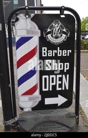 Insegna per un barbiere con il tradizionale palo del barbiere rosso, bianco e blu: 'Barbiere aperto'. Foto Stock