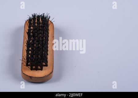 spazzola lustrascarpe con manico in legno su sfondo blu chiaro Foto Stock